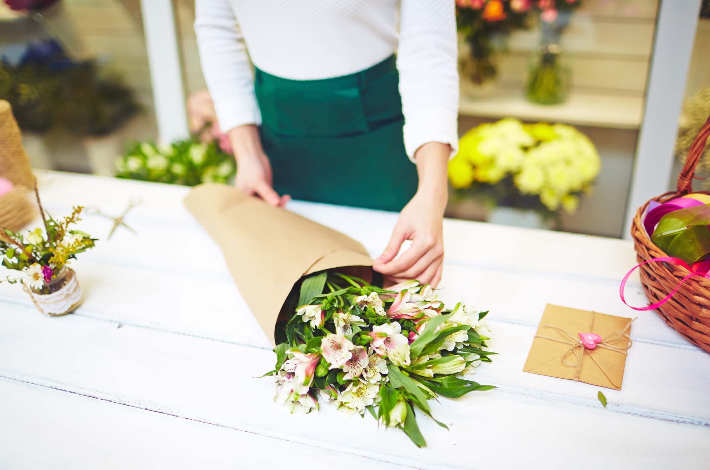 Female florist wrapping up bouquet of white amaryllises